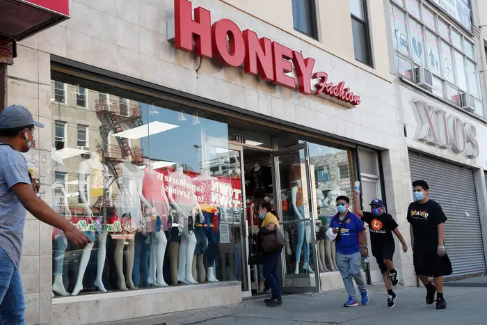 Pedestrians pass by Honey Fashion, a women's clothing store in the Sunset Park.